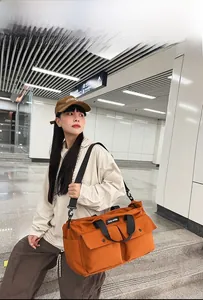 Close-up of orange canvas tote bag with two front flap pockets and wide black strap