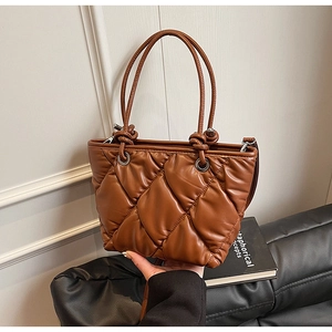 Détail d'un sac cabas marron matelassé avec surpiqûres en losange et œillets argentés