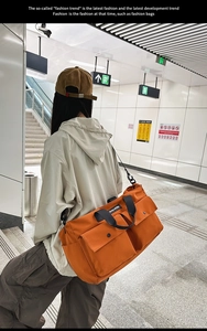 Orange large capacity canvas tote bag with multi-pockets shown in a street commute scene
