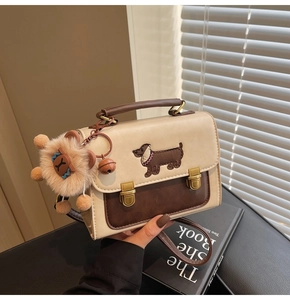 Close-up of contrast color crossbody bag with dachshund embroidery and lion plush charm