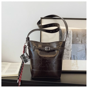 Detail of vintage brown bucket bag with decorative buckle and unique camera charm