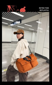 Orange canvas tote bag with multi-pocket design shown on model in urban subway station