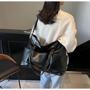 Detail of a black large-capacity tote bag with polished texture and adjustable straps
