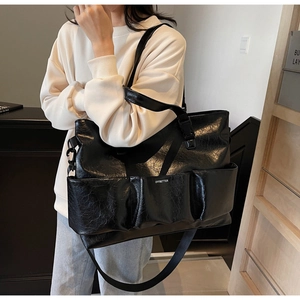 Detail of black glossy tote bag featuring three front pockets and wrinkled texture finish