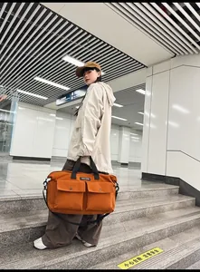 Close-up of orange canvas tote bag with front flap pockets and adjustable black straps