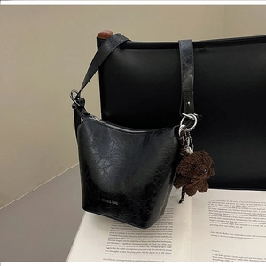 Detail of glossy black vintage bucket bag with silver zipper and cute plush bear charm