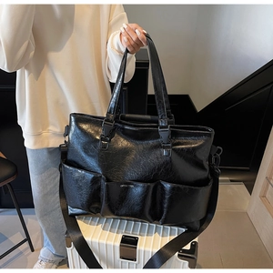 Detail view of large black glossy tote bag with pleated PU texture and multi-pocket design