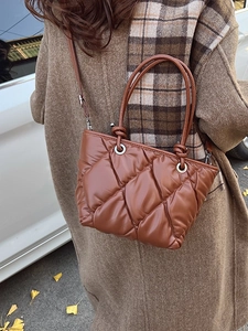 Sac seau matelassé marron caramel à motif losanges présenté dans un décor d'automne