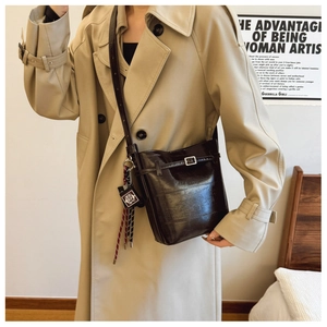 Detail of vintage coffee brown leather bucket bag with braided strap and metal buckle charm