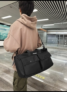Detail of black nylon tote bag with functional pockets and Grey-white brand label