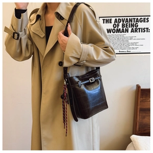 Detail of dark brown faux crocodile bucket bag with decorative scarf and metal buckle