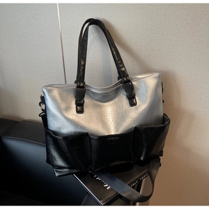 Macro detail of silver metallic and black leather tote bag with functional pockets
