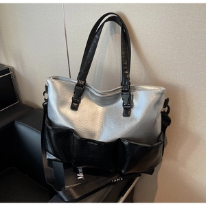 Detail of silver metallic tote bag with three black exterior pockets and brand logo