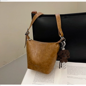 Close-up of brown pleated vintage bucket bag with a cute plush dog charm on a chair