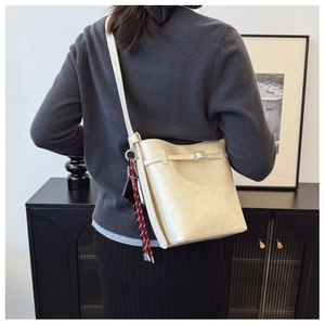 Detail of cream leather bucket bag with buckle straps and red-white woven ornament