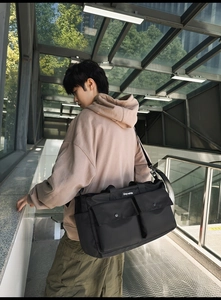 Detail of black nylon tote bag with two front flap pockets and adjustable shoulder strap