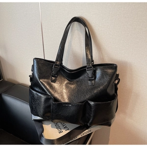 Detail of black tote bag with wrinkled leather texture and front pocket silver logo