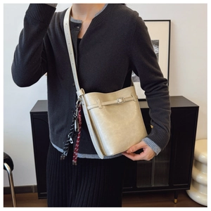 Beige bucket bag worn by model showing size proportion and woven tassel detail
