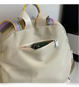 Detail of beige nylon backpack showing side zipper pocket and colorful strap with logo