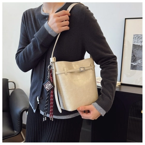 Detail of cream leather bucket bag with silver buckle and Holy Bible book pendant charm