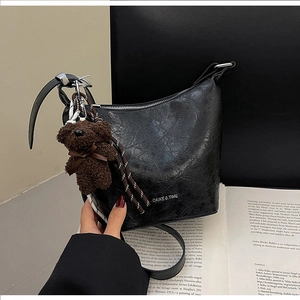 Fashionable black textured bucket bag with teddy bear pendant and DA&T branding