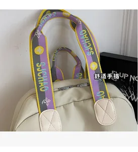 Close-up of the beige nylon backpack featuring a colorful woven handle and leather patches
