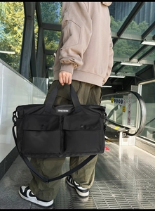 Detail view of large black canvas tote bag with functional multi-pockets and shoulder strap