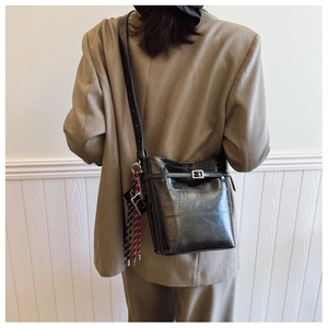 Detailed back view of a black glossy leather bucket bag with silver buckle and rope pendant