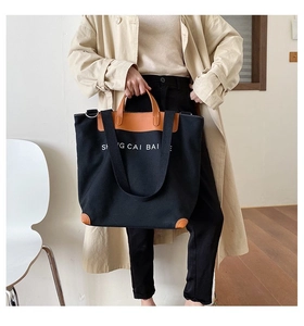 Detail of large black canvas tote with brown leather trim and reinforced corners
