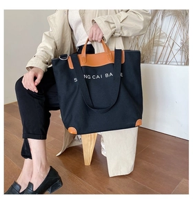 Detail of the high-capacity canvas tote bag with brown leather handles and base accents