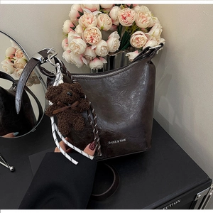 Detail of vintage brown bucket bag with a cute teddy bear charm and silver zipper