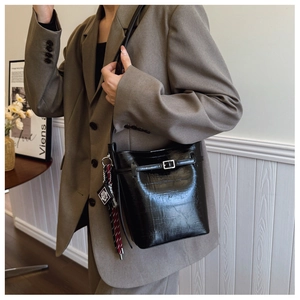 Detailed shot of glossy black bucket bag with silver buckle and crocodile texture