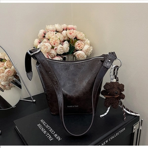 Detail of dark brown hobo bag with plush bear charm and luxury logo texture