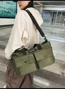 Detail of olive green nylon tote bag featuring large front pockets and water-resistant fabric