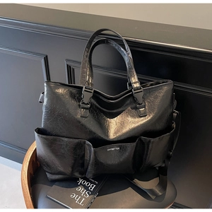 Close-up of black tote bag with retro cracked leather texture and functional front pockets