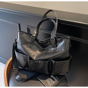 Detail of black faux leather tote with triple front pockets and adjustable strap