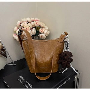 Detail of caramel bucket bag with vintage wrinkled texture and teddy bear pendant