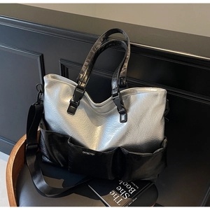 Close-up of silver crinkled tote bag with black pockets and OFFBETTER logo on a chair