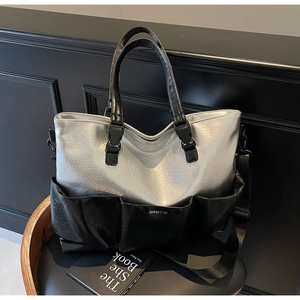 Detail of silver and black tote bag with front pockets and adjustable fabric strap