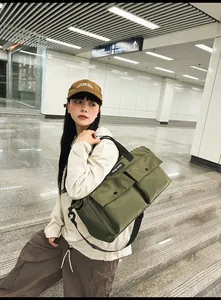 Detail of army green canvas tote bag with large buckled pockets and adjustable strap