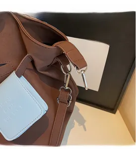 Dettaglio del gancio in metallo argento e tracolla regolabile di una borsa tote marrone