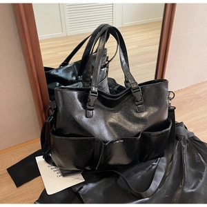 Detail of black oil wax leather tote bag with multi-pocket design and adjustable strap