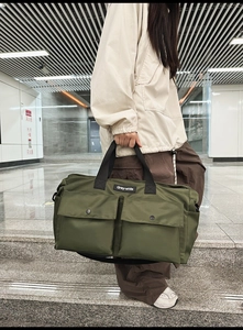 Detail of army green canvas tote bag with dual front flap pockets and adjustable strap