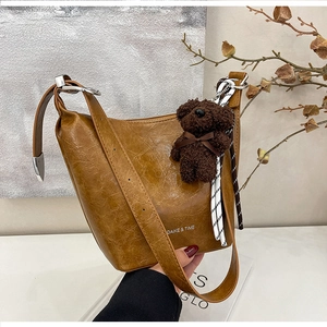 Detailed close-up of brown bucket bag with silver hardware and plush bear charm