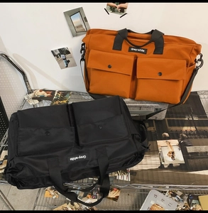 Detailed view of large canvas tote bags in orange and black with tactical dual front pockets