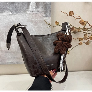 Detail of retro leather bucket bag with plush bear charm and AIKE & TIME logo