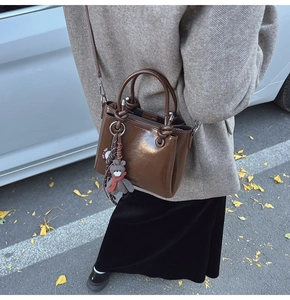 Détail du sac seau en cuir marron brillant avec breloque ours pour l'hiver