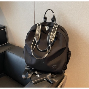 Close-up of black nylon backpack featuring white lettered straps and side pocket