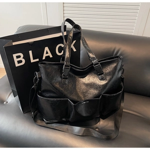 Detail of black faux leather tote bag with multi-pocket design and adjustable strap