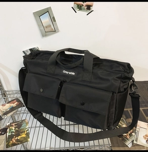 Detail of black canvas tote bag showing reinforced handles and front utility pockets